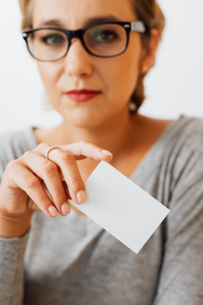 Crafting Captivating Headlines: Your awesome post title goes here Close-up of a woman holding a blank business card, ideal for branding use.